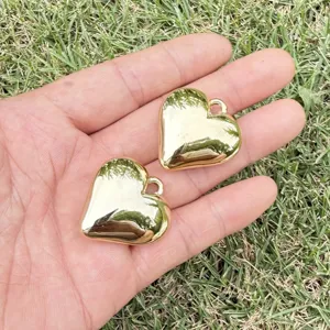 Macro detail of two golden smooth heart-shaped CCB charms for DIY jewelry and necklaces