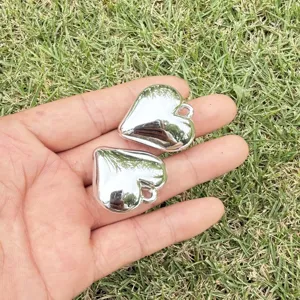Detailed macro view of two silver heart-shaped pendants for DIY jewelry making.