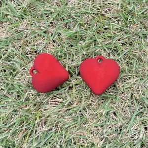 Macro view of red matte heart-shaped charms for DIY jewelry making on natural grass