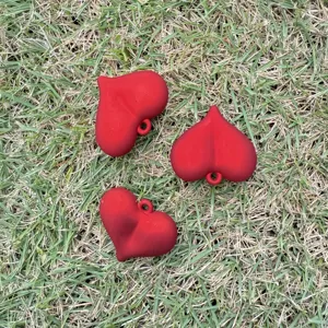 Close-up view of three matte red heart-shaped charms for DIY necklace and bracelet.