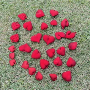 A variety of red heart-shaped charms scattered on green grass for DIY jewelry making