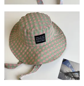Dettaglio cappello da pesca a quadri rosa e verde, elegante cappello estivo a tesa larga.