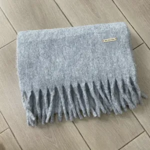 Grauer Winter Wollmischung Schal Detailansicht mit groben Fransen und elegantem Metalllabel.