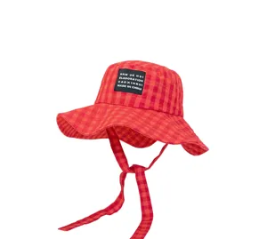 Dettaglio cappello bucket a quadri rosso e bianco, tesa larga con laccio ed etichetta.
