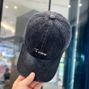 Nahaufnahme einer dunklen Jeans-Baseballkappe mit feiner weißer Stickerei und Detailtextur.