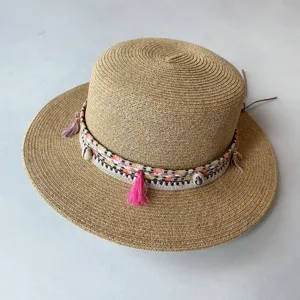 Detailansicht des sommerlichen Strohhuts mit BOHO-Band, Quasten und Muscheln verziert.