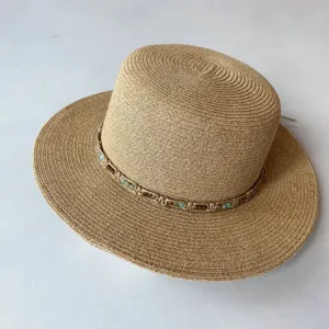 Detailansicht eines beigen Strohhutes mit flacher Krone und Perlenflechtband für den Sommerurlaub.