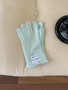 Primo piano di guanti invernali in maglia verde chiaro touch screen con etichetta logo.