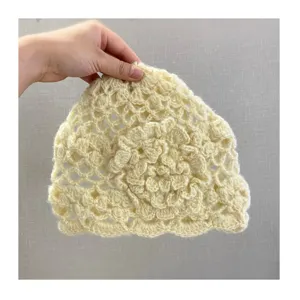 Vista dettagliata di un berretto in maglia uncinetto beige con motivo floreale 3D.