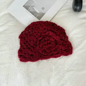 Primo piano del berretto in maglia uncinetto rosso scuro, berretto mohair vintage floreale.