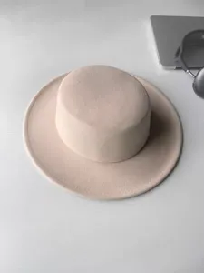 Detailansicht eines stylischen rosa Flachtop-Wollhutes mit breiter Krempe für Winter.