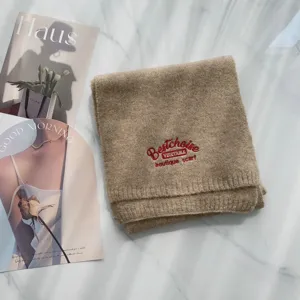 Nahaufnahme eines kuscheligen Wollmischgewebe-Strickschals mit roter Bestickung Detail.