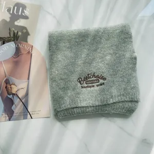 Nahaufnahme des grauen Strickschals aus Wolle mit stilvoller Stickerei und weicher Textur.