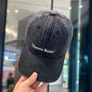 Detailansicht der Washed-Denim-Baseballkappe mit weißer Stickerei und gebogenem Schirm.
