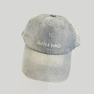 Detailansicht der Used-Look Jeans Baseballcap mit weißer Hustle Hard Stickerei und Ösen.