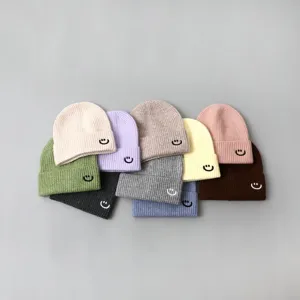 Detailed view of colorful kids knitted beanie hats featuring cute embroidered smile face designs.