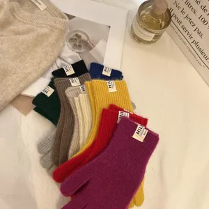 Primer plano de coloridos guantes de lana tejidos con pequeñas etiquetas, cálidos y acogedores.