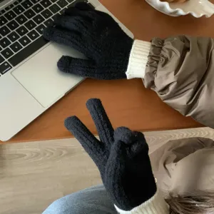 Close-up van zwarte gebreide touchscreen handschoenen met witte ribboorden op het bureau.