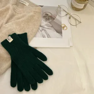 Primer plano de guantes de punto verde oscuro, textura cálida de lana de invierno.