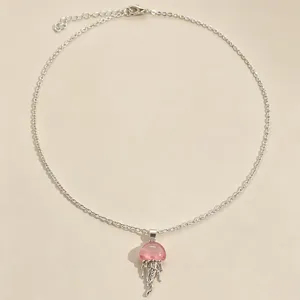 Close-up detail of a silver-tone chain necklace featuring a cute pink glass jellyfish pendant.