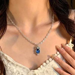 Gros plan sur le collier pendentif hibou en argent avec un beau cristal bleu scintillant.