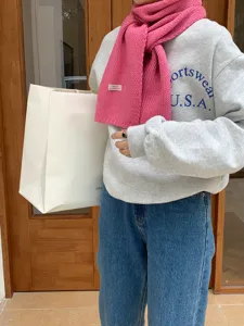 Detailansicht des weichen, kuscheligen rosa Strickschals für den Winter mit Etikett.