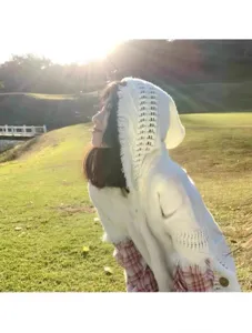 Gros plan en extérieur d'un poncho en tricot à capuche bohème avec franges, pour voyage.