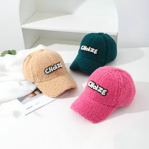 Detail shot of fuzzy sherpa baseball caps in khaki, green, and pink with letter embroidery.