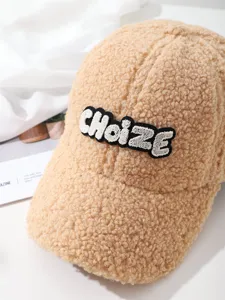 Detail shot of beige teddy fleece baseball cap with embroidered letter design for winter style.