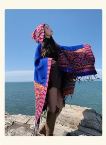 Vue détail de la cape bleue à capuche et franges avec motifs floraux ethniques dehors.