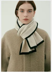 Dettaglio ravvicinato della comoda sciarpa in maglia da donna con raffinato bordo a contrasto.