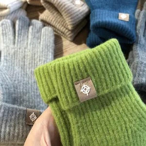 Detailansicht winterlicher einfarbiger Strickhandschuhe mit geripptem Bündchen und Label.