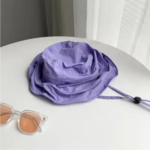 Gros plan détaillé d'un chapeau bob d'été violet avec cordon réglable sur une table propre.