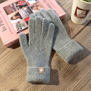 Nahaufnahme von kuscheligen Strick-Winterhandschuhen in Grau mit stilvollem Aufnäher.