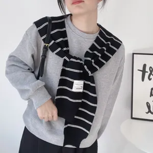 Detailed view of the stylish striped knitted shawl worn over a grey sweatshirt, perfect.
