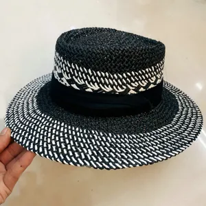 Détail de chapeau de paille noir et blanc, design plat rétro chic avec large bord pour été.