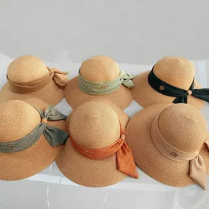 Vue détaillée du chapeau de paille d'été pour femmes avec nœud en tissu élégant et logo M métallique.