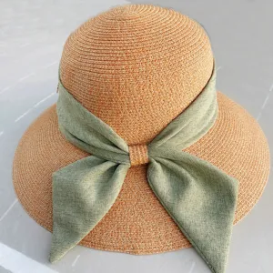 Gros plan détaillé du chapeau de soleil en paille orange chic avec un nœud en tissu vert.