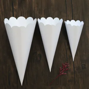 Detailed view of white scalloped paper cones in three sizes for wedding confetti and DIY parties.