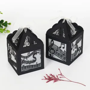 Boîtes en papier ajourées noires avec notes de musique et touches de piano pour fête.