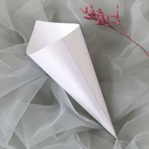 Detalle de primer plano de elegante cono de papel blanco decorado con rama floral.