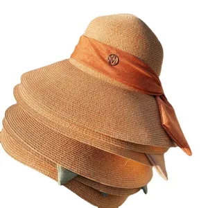 Chapeau de paille femme grand bord ete plage avec un noeud elegant et logo en metal.