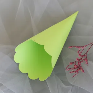 Close-up detail of light green paper confetti cone with scalloped edge for wedding.