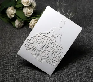 Detalle de tarjeta de invitación de boda blanca cortada por láser con elegante vestido.