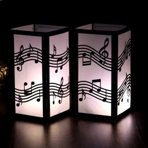 Close-up detail of laser-cut musical note paper lampshade, warm glowing night light decor.