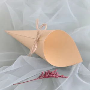 Detailed shot of a brown kraft paper confetti cone with twine bow on white tulle fabric.