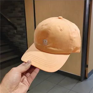 Detailed shot of the orange casual baseball cap featuring chic R letter embroidery for sunny days.