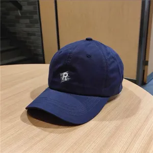 Detailed shot of a navy blue baseball cap with white R embroidery on a wooden table.