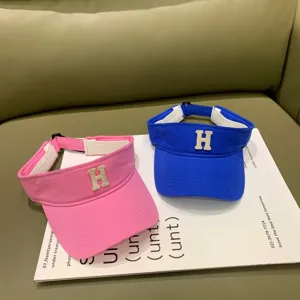 Detailansicht modischer, leerer Sonnendachmützen in Rosa und Blau mit Buchstabenstickerei.