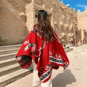 Detailed outdoor view of the red ethnic style winter shawl cloak, showing back pattern.